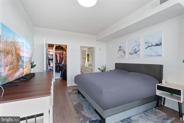 bedroom featuring dark hardwood / wood-style flooring, a walk in closet, ensuite bathroom, and a closet