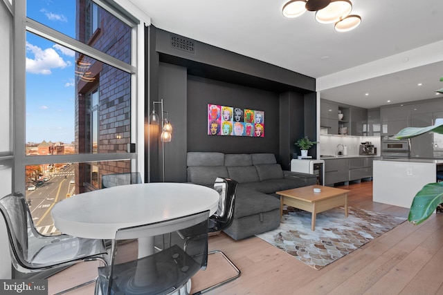 living room featuring sink, light hardwood / wood-style floors, and a wall of windows