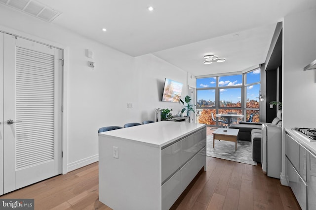 kitchen with white cabinets, a center island, and light wood-type flooring