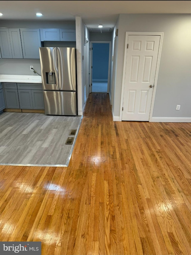 kitchen featuring stainless steel fridge with ice dispenser, light wood-type flooring, and gray cabinetry