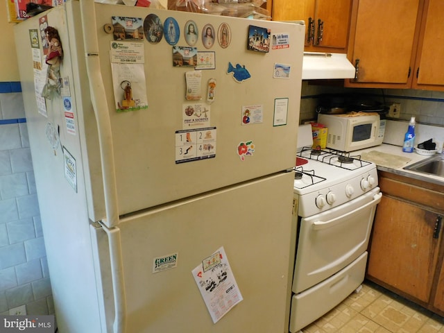 kitchen with ventilation hood, white appliances, and sink