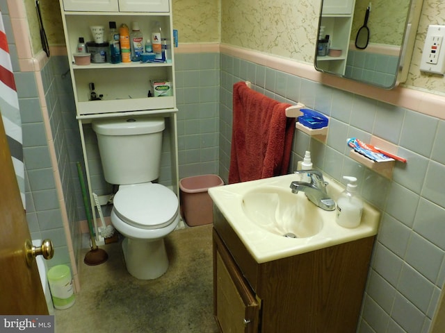 bathroom with vanity, toilet, and tile walls