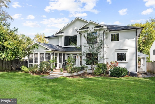 back of house with a sunroom, cooling unit, and a lawn