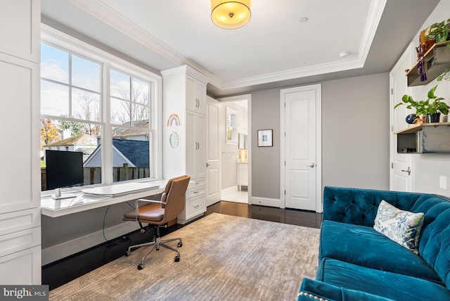 home office featuring dark wood-type flooring, ornamental molding, and built in desk