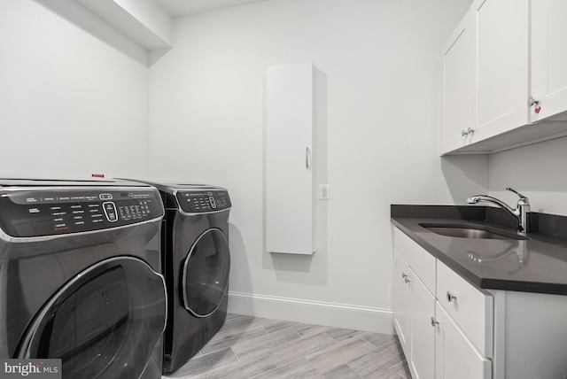 washroom with cabinets, sink, and washing machine and clothes dryer