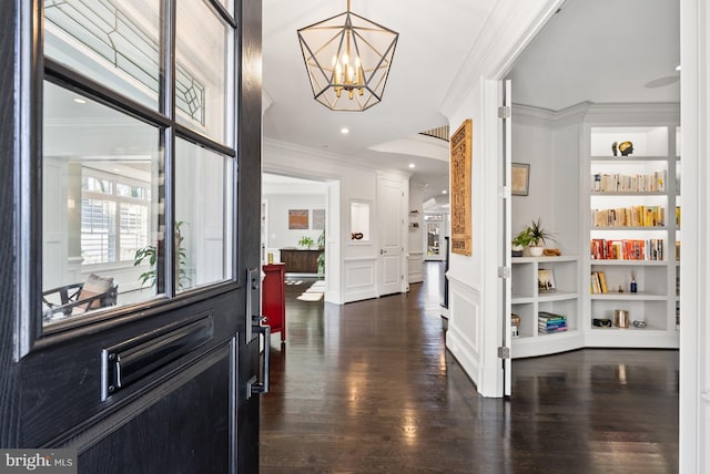 entryway featuring dark hardwood / wood-style floors, ornamental molding, and a notable chandelier