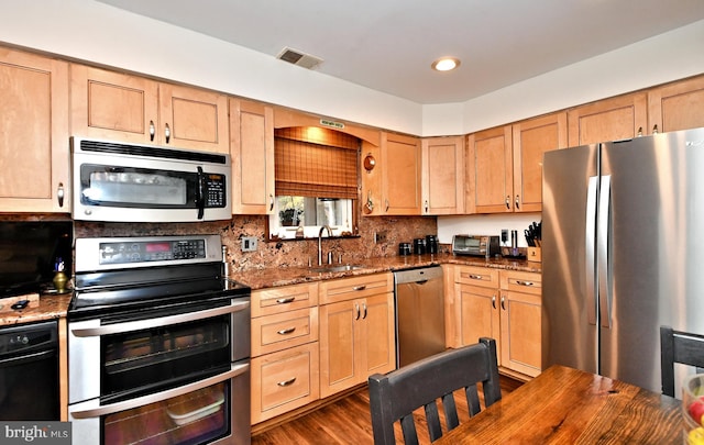 kitchen featuring tasteful backsplash, dark stone counters, stainless steel appliances, sink, and dark hardwood / wood-style floors