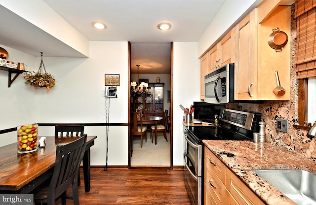 kitchen featuring light stone countertops, appliances with stainless steel finishes, dark hardwood / wood-style flooring, sink, and a chandelier