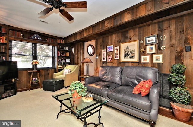 living room featuring carpet flooring, ceiling fan, and wooden walls