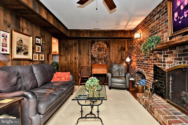 carpeted living room featuring ceiling fan, wood walls, and a fireplace