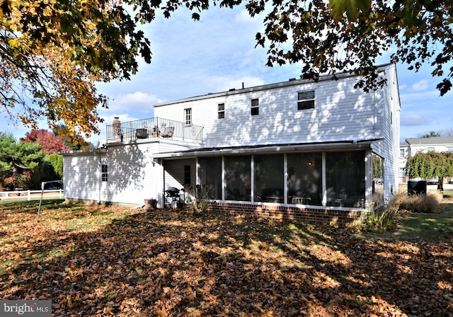 rear view of property featuring a sunroom and a balcony