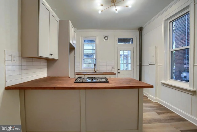 kitchen with butcher block counters, white cabinetry, gas stovetop, wood-type flooring, and decorative backsplash