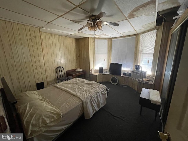 carpeted bedroom featuring ceiling fan and wooden walls