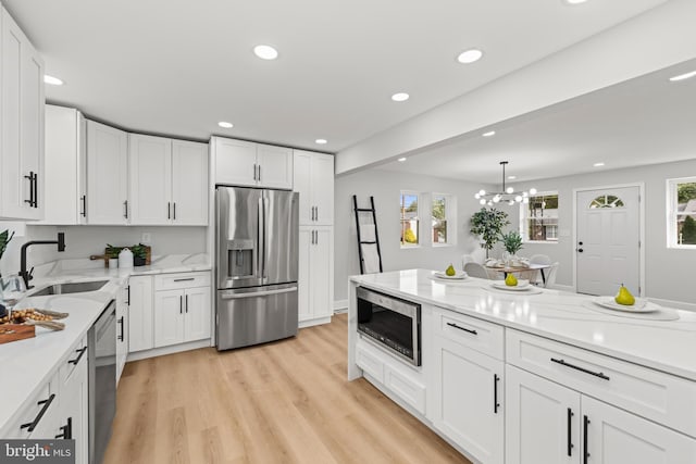 kitchen with a notable chandelier, light wood-type flooring, white cabinetry, and stainless steel appliances