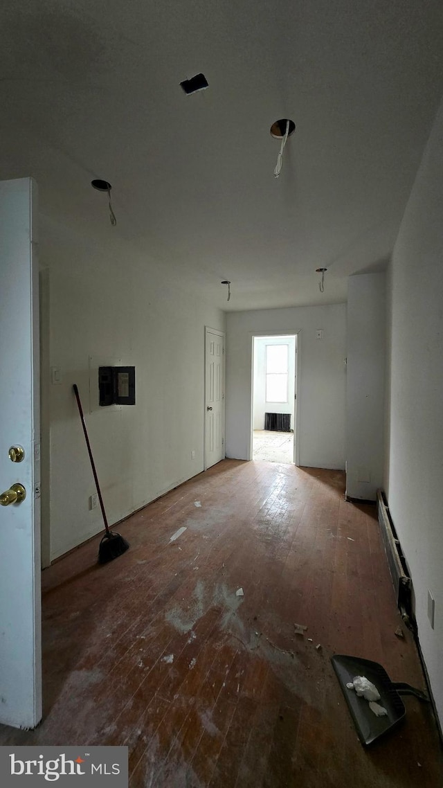 unfurnished room with radiator, electric panel, and hardwood / wood-style flooring