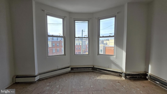 empty room with baseboard heating and a healthy amount of sunlight