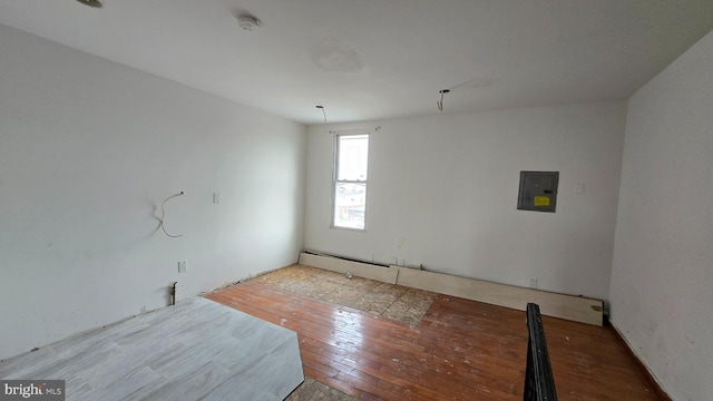 spare room featuring electric panel and light hardwood / wood-style floors