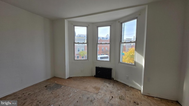 empty room with light hardwood / wood-style floors and radiator heating unit