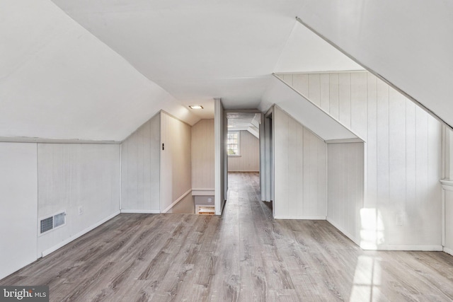 bonus room with wood walls, light hardwood / wood-style flooring, and lofted ceiling