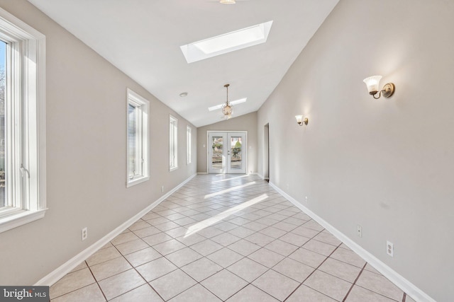 interior space with vaulted ceiling with skylight, a chandelier, light tile patterned floors, and french doors