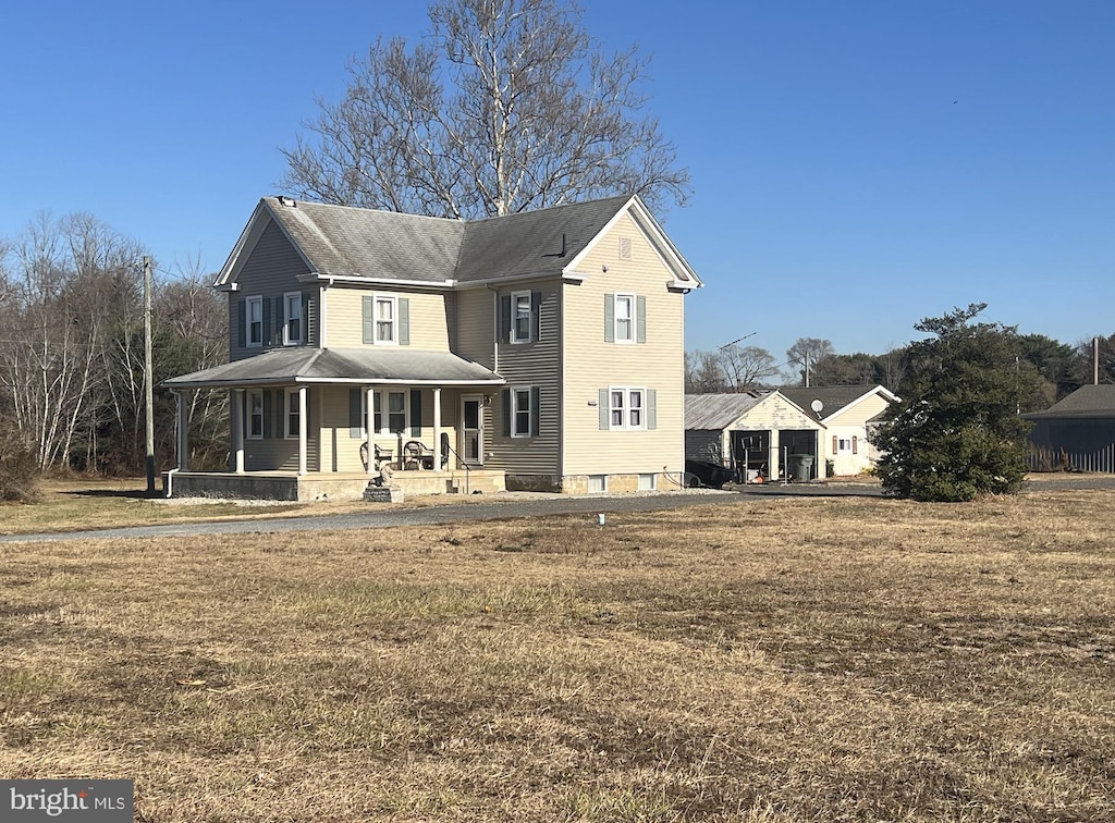 rear view of property featuring a porch and a lawn