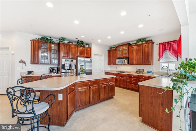 kitchen featuring a breakfast bar, a center island, stainless steel appliances, and sink