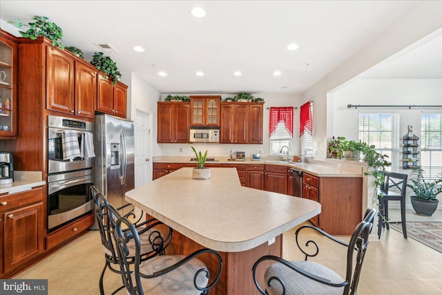 kitchen featuring a kitchen breakfast bar, kitchen peninsula, sink, and appliances with stainless steel finishes