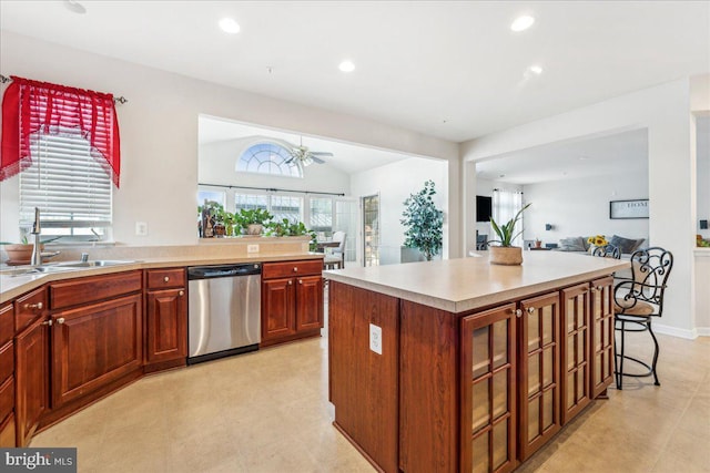 kitchen with ceiling fan, sink, stainless steel dishwasher, vaulted ceiling, and a kitchen island