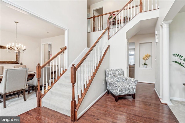 staircase featuring a chandelier, hardwood / wood-style floors, and a high ceiling