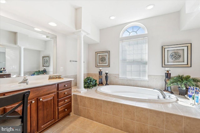 bathroom featuring ornate columns, vanity, tile patterned floors, and tiled tub