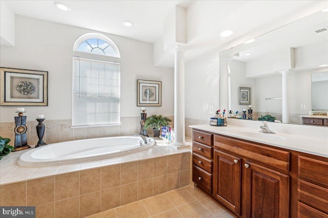 bathroom with tile patterned flooring, vanity, and tiled bath