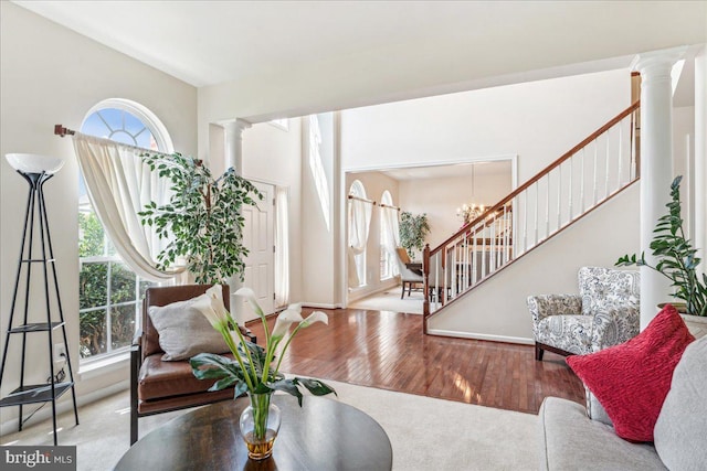 living room with a chandelier, light wood-type flooring, and decorative columns