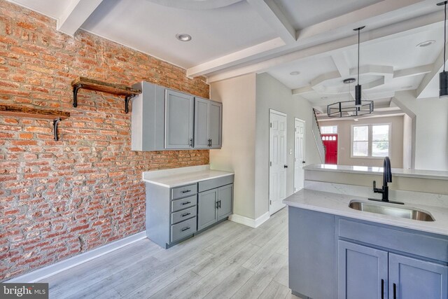 kitchen featuring sink, hanging light fixtures, light hardwood / wood-style flooring, brick wall, and gray cabinets