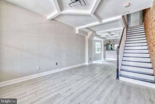 unfurnished living room with beamed ceiling and light wood-type flooring