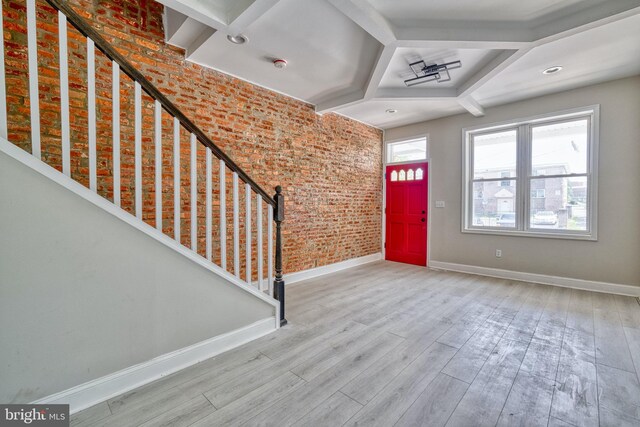 foyer entrance with light hardwood / wood-style flooring and brick wall