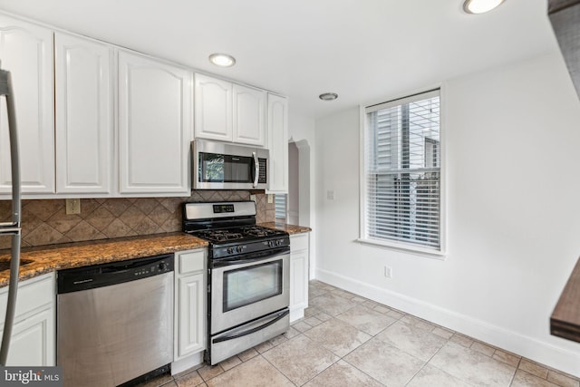 kitchen with backsplash, dark stone counters, white cabinets, appliances with stainless steel finishes, and light tile patterned flooring