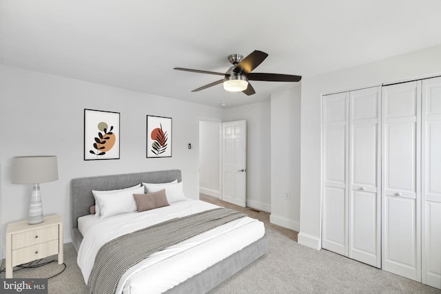 bedroom with ceiling fan, light carpet, and a closet