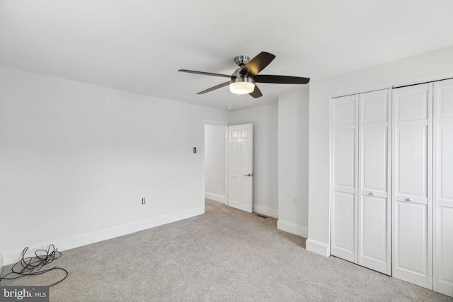 unfurnished bedroom with a closet, ceiling fan, and light colored carpet