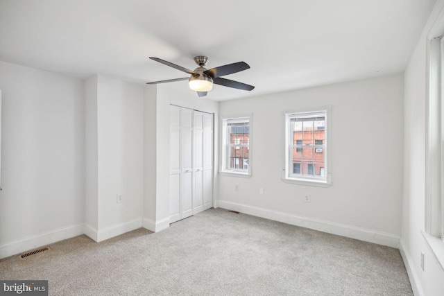 unfurnished bedroom with ceiling fan, a closet, and light colored carpet