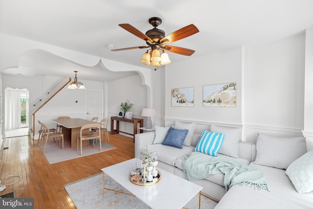 living room with ceiling fan with notable chandelier and light wood-type flooring