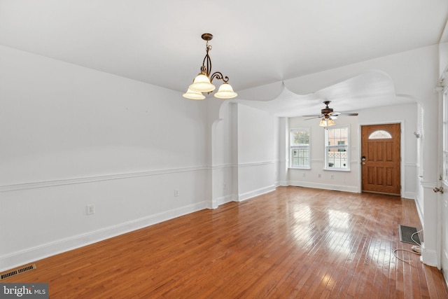 interior space with ceiling fan with notable chandelier and wood-type flooring