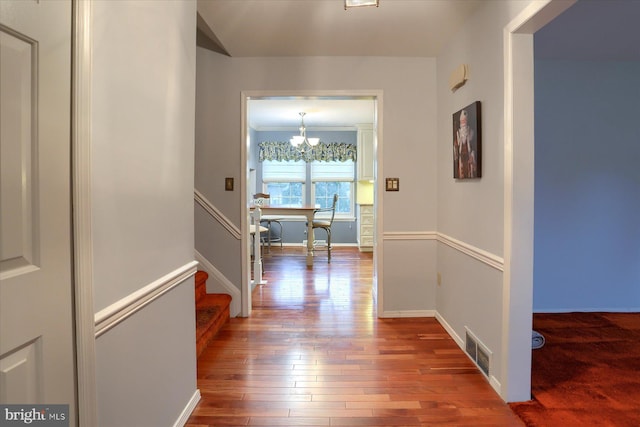 hall featuring crown molding, a notable chandelier, and hardwood / wood-style flooring