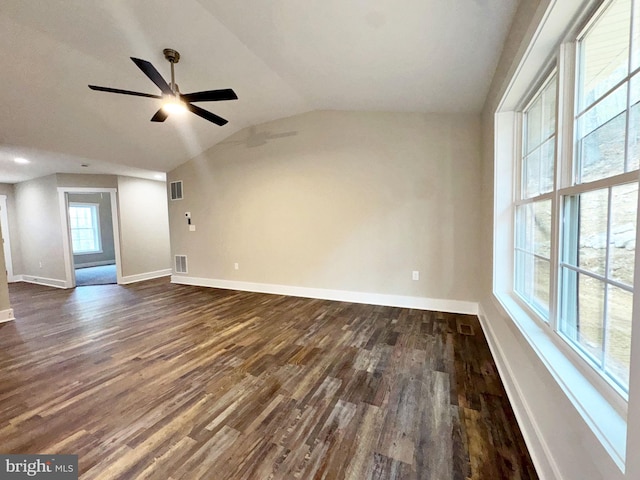 spare room featuring vaulted ceiling, visible vents, a ceiling fan, dark wood-type flooring, and baseboards