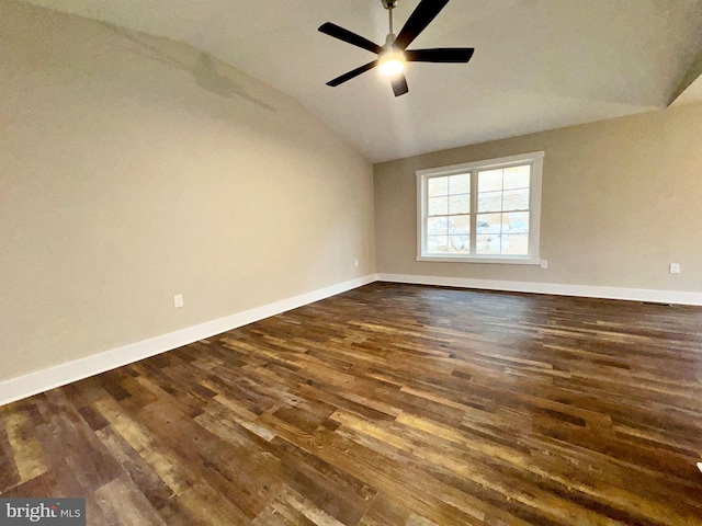 spare room featuring dark wood-type flooring, lofted ceiling, baseboards, and ceiling fan
