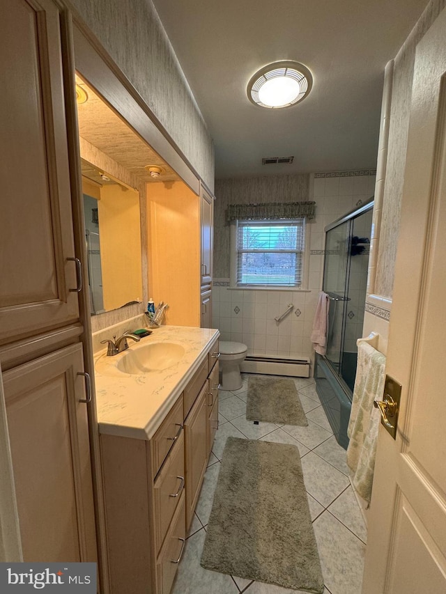 full bathroom featuring vanity, a baseboard heating unit, tile patterned floors, toilet, and enclosed tub / shower combo