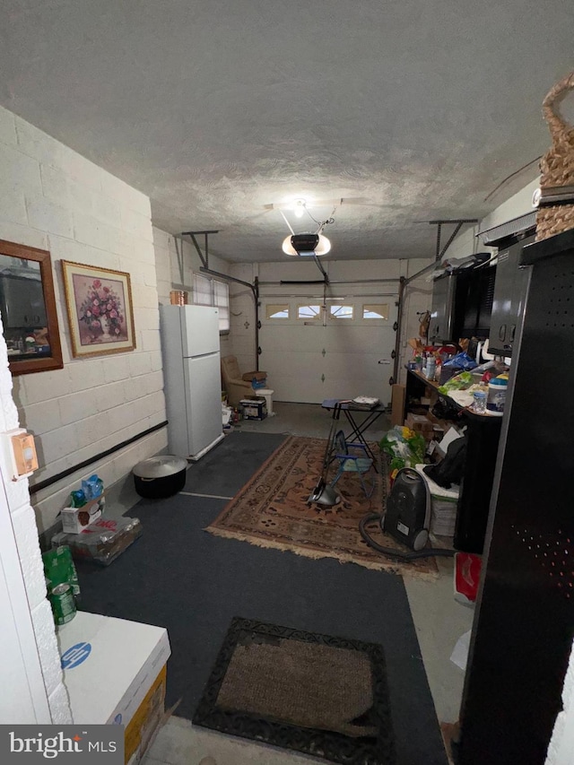 garage with a garage door opener and white refrigerator