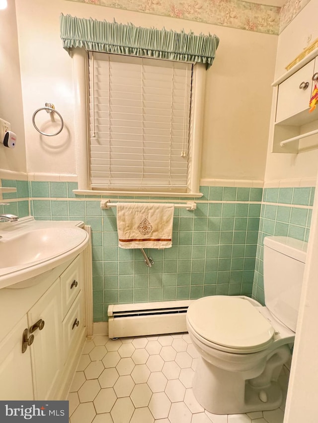 bathroom with baseboard heating, tile patterned floors, toilet, vanity, and tile walls