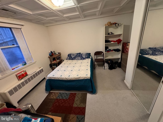 bedroom with carpet, radiator heating unit, coffered ceiling, and a closet