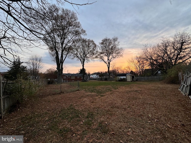 yard at dusk featuring a storage shed