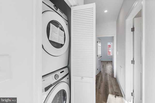 laundry room with wood-type flooring and stacked washer and dryer